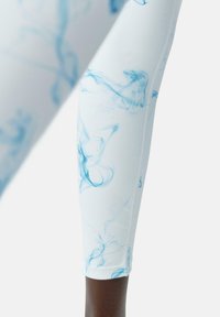 Hvite leggings med et blått røykemønster, laget av elastisk materiale; har en jevn tekstur og tettsittende design med en oppbrett i kanten.
