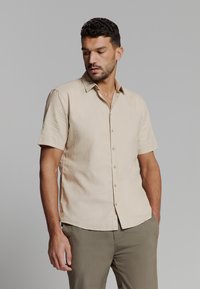 Korte mouwen beige button-up shirt met een kraaghals, gemaakt van lichte stof, met een rechte zoom en subtiele textuur.