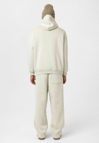 Lichtbeige oversized hoodie en bijpassende joggers, gemaakt van zachte stof. De hoodie heeft een grote achterzak en ribgebreide manchetten, met een eenvoudig ontwerp.