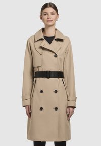 Beige trench coat with double-breasted buttons, wide collar, and set-in belt. Features side pockets and long sleeves with buttoned cuffs.