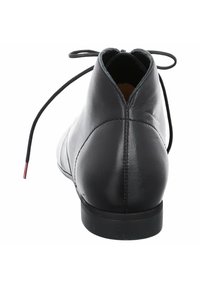 Bottine en cuir noir avec un bout rond, un talon plat et un système de laçage à l'arrière. Présente une texture lisse et des détails minimaux.