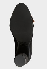 Černá semišová lodička na vysokém podpatku s texturovanou podrážkou a cylindrickým podpatkem. Velikost 37 vyražena uvnitř, s hnědým akcentem na pásku.