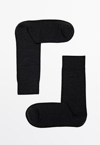 Schwarze, gestrickte Socken in flacher Anordnung präsentiert. Weiche Textur, verstärkte Bündchen und glatte Verarbeitung. Keine Muster oder sichtbaren Logos.