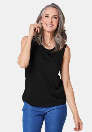Top nero senza maniche con scollatura rotonda, realizzato in tessuto morbido, con una vestibilità comoda. Abbinato a jeans in denim blu.