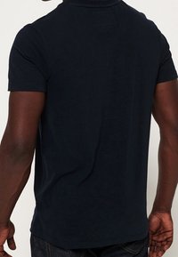 Donkerblauwe polo met korte mouwen van een katoenmix, met een klassieke kraag, een gladde textuur en een rechte zoom. Geen zichtbare logo's of patronen.