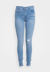 Jeans ajustados en denim azul claro, con un desgaste en forma de corazón en la rodilla derecha, cinco bolsillos y una cinturilla clásica con cierre de botón.