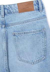 Jean en denim bleu clair avec une étiquette en cuir portant la mention "Galileo Denim Collection" et une poche arrière avec des détails de double couture.