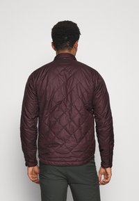 Bordó prošívaná bunda s dlouhými rukávy, stojáčkovým límcem, texturovaným vzorem a manžetami na knoflíky. Lehký, izolační design.