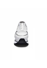 Sneaker bianco con una tomaia in rete testurizzata, suola nera a contrasto e dettagli argentati. Presenta lacci tradizionali e un tallone rinforzato.
