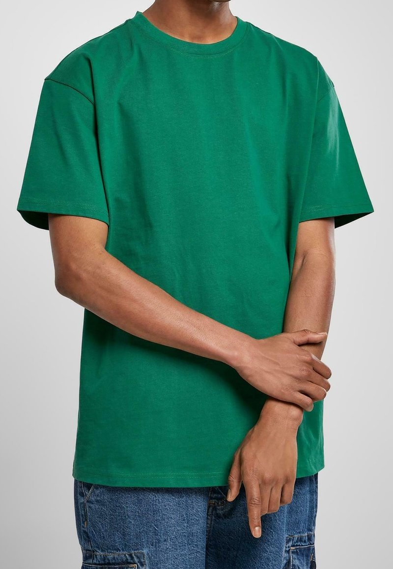 Zelené tričko s kulatým výstřihem vyrobené z měkké bavlny s krátkými rukávy. Má uvolněný střih, čisté švy a žádné viditelné logo ani vzory.