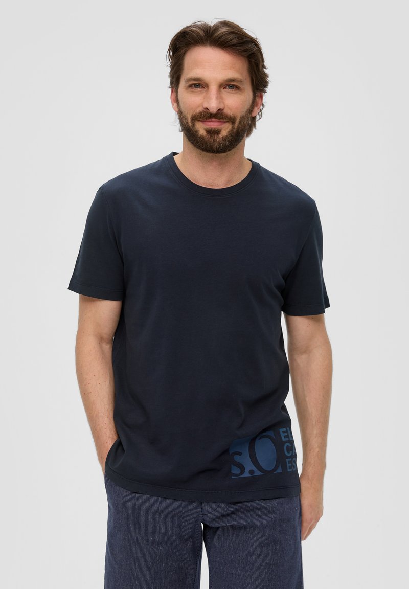 Navyblauw katoenen t-shirt met korte mouwen, voorzien van een ronde hals en een logo-inzet in donkerblauw aan de onderlinkerkant. Glad oppervlak.