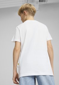 Valkoinen puuvillainen t-paita lyhyillä hihoilla, rento malli ja kaareva helma. Säilyttää pienen Ferrari- ja Puma-logon sivussa.