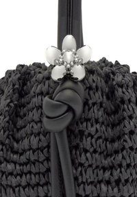 Bolso de mano negro tejido con un patrón texturizado, con una correa de cuero negro anudada y un acento de flor plateada con detalles de perlas.