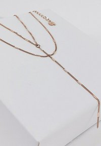 Collar de oro rosa en capas con un delicado diseño de cadena, que presenta eslabones texturizados y un cierre ajustable. Presentado en una caja blanca.