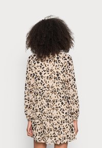 Leopardenmuster-Kleid aus leicht beigem Stoff, mit langen Ärmeln, einer gerafften Taille und einem schwingenden Rock in gestuften Design.