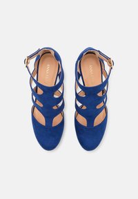 Blue suede high-heeled shoes with cut-out design and ankle strap. Featuring a smooth texture and a rounded toe, ideal for formal occasions.
