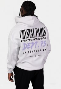 Bílá mikina s kapucí, na zadní straně s velkým černým a fialovým textem, obsahující designy "CRYSTAL PARIS", "FIGHTFORFREEDOM" a "DEPT. 75".