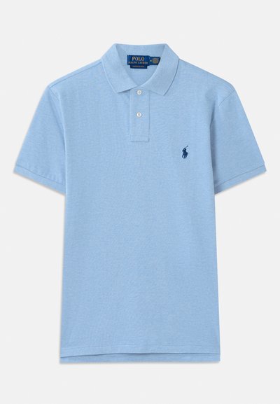 Polo din bumbac de culoare albastră deschisă. Prezintă o deschidere cu trei nasturi și un logo brodat de culoare albastră închisă pe partea stângă a pieptului. Mâneci scurte.