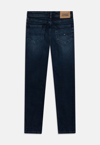 Granatowe dżinsy w wąskim kroju, z dwoma tylnymi kieszeniami, skórzaną metką z napisem "Tommy Hilfiger" oraz prostymi nogawkami.