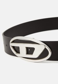 Black leather belt with a silver oval buckle featuring a cut-out design. The belt has visible holes for size adjustment.