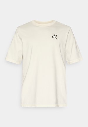 Krém színű, pamutból készült póló, rövid ujjú és kerek nyakú kivitelben. A mellrészen apró fekete hímzett mintával díszített.