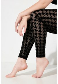 Leggings neri trasparenti con un motivo a houndstooth in tessuto testurizzato, con un design aderente e taglio alla caviglia.
