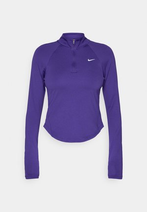 Haut de sport long à manches violettes avec un col haut et une demi-fermeture éclair. Il présente un ourlet crop et un logo Nike blanc sur la poitrine. Tissu extensible.