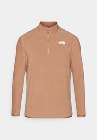 Pullover in pile marrone con colletto alto, zip frontale a un quarto, maniche lunghe e logo bianco sul petto. Texture liscia e vestibilità regolare.