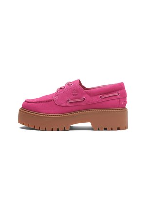 Pink suede boat shoe with a thick, brown platform sole, featuring lace loops and logo detail on the side. Textured and sporty design.