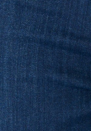 Primo piano di tessuto in denim blu scuro che mostra la trama a tessitura diagonale e lievi variazioni di colore.