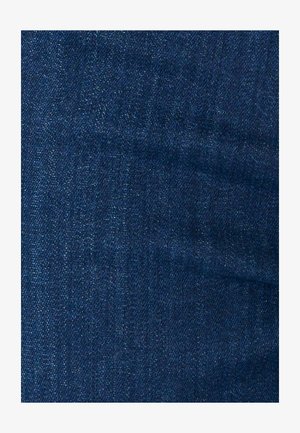 Primo piano di tessuto in denim blu scuro che mostra la trama a tessitura diagonale e lievi variazioni di colore.