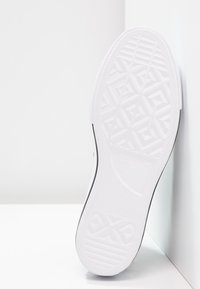 Hvit gummisåle til sneakers med geometrisk mønster, jevn tekstur og en liten svart aksentlinje langs kanten. Merkevarelogo til stede.