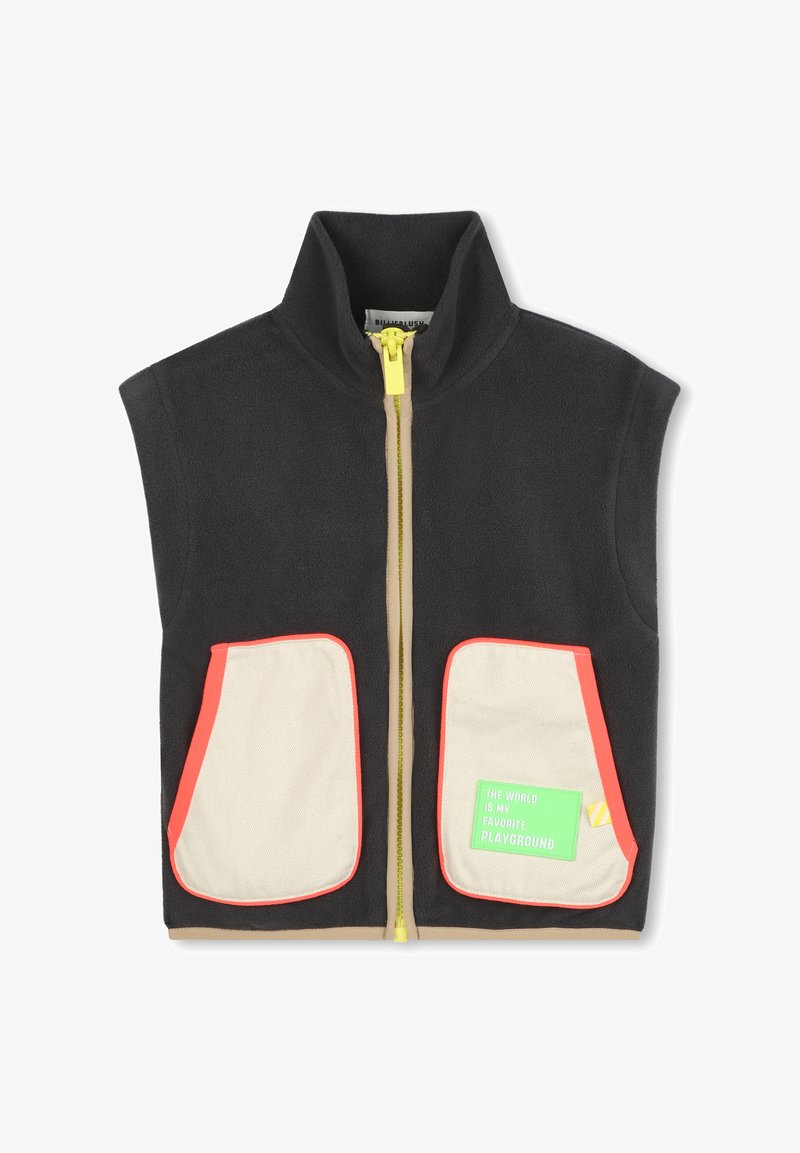 Chaleco de forro polar en gris oscuro con un cuello alto, cremallera amarilla en la parte delantera, dos bolsillos crema con bordes rojos y una etiqueta verde adjunta.