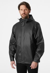 Chaqueta negra impermeable con capucha, que cuenta con una textura suave, cierre frontal con cremallera y bolsillos laterales, diseñada para uso al aire libre.