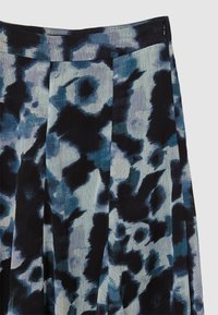 Jupe plissée avec un motif floral abstrait marine, noir et gris et fermeture éclair discrète sur le côté.