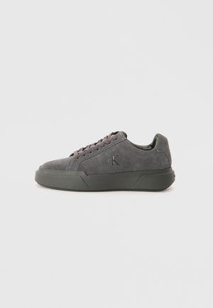 Sneaker in suede grigio scuro con superficie testurizzata, suola in gomma piatta e lacci tonali. Presenta un logo inciso su un pannello laterale.