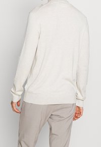 Ljusbeige långärmad tröja med rund halsringning, ribbade muddar och något avsmalnande nederkant. Texturerat stickat tyg med minimalistisk design.