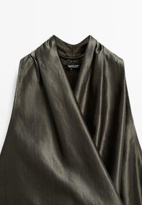 Sleeveless, dark olive green top made of smooth, shiny fabric with a draped design and a high collar, featuring a tag inside.