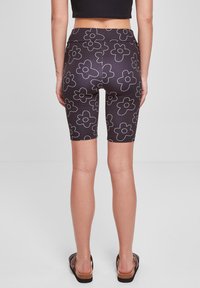 Fekete, magas derekú biciklis nadrág fehér virágmintával. Rugalmas anyagból készült, térd felett végződik és sima felületű.