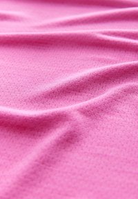 Tessuto rosa testurizzato con superficie liscia, che mostra motivi sottili e un aspetto morbido, drappeggiato per evidenziare le pieghe e i contorni.