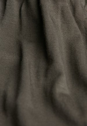 Donkergrijze stof met een zachte, geribbelde textuur, waarin subtiele plooien en variërend licht en schaduw zichtbaar zijn, wat diepte en dimensionaliteit aanduidt.