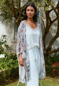 Lightweight, floral-patterned kimono with lace accents, layered over a white, sleeveless top and matching pants. Soft, flowing fabric.