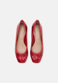 Paire de ballerines en cuir verni rouge avec bouts ronds et petits nœuds sur un fond blanc, taille 37.