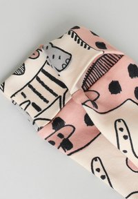 Bandeau en tissu à motifs arborant des couleurs rose et crème avec des formes et designs abstraits noirs. Le matériau semble doux et flexible.