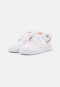 Vita lädersneakers med rosa och guld detaljer, snörning, perforerat tåparti och gummisula. Har en sidoparta med swoosh-logotyp.