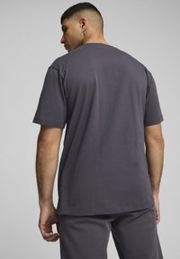 Grijze katoenen t-shirt met een ronde hals en korte mouwen. De stof lijkt zacht, lichtjes textuur, met een relaxte pasvorm. Minimalistisch ontwerp.