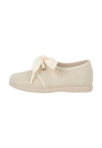 Beige knit shoe with a rounded toe and a textured upper. Features a decorative bow at the front and a smooth rubber sole.