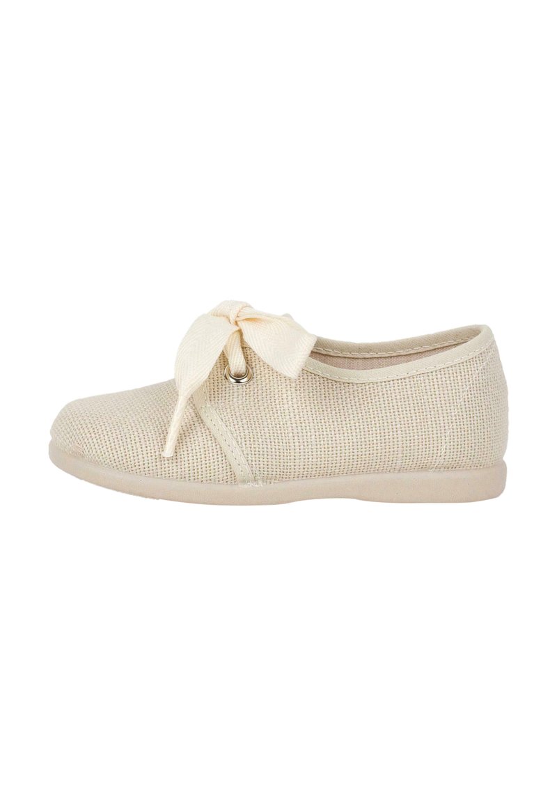 Beige knit shoe with a rounded toe and a textured upper. Features a decorative bow at the front and a smooth rubber sole.
