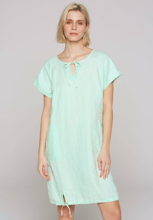 Mint green linen dress with short sleeves, keyhole neckline with tie detail, side pockets, and a small slit at the hem.