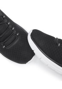 Schwarze Mesh-Sportschuhe besitzen ein strukturiertes Obermaterial, elastische Schnürsenkel und weiße Gummisohlen mit einer leichten Krümmung.